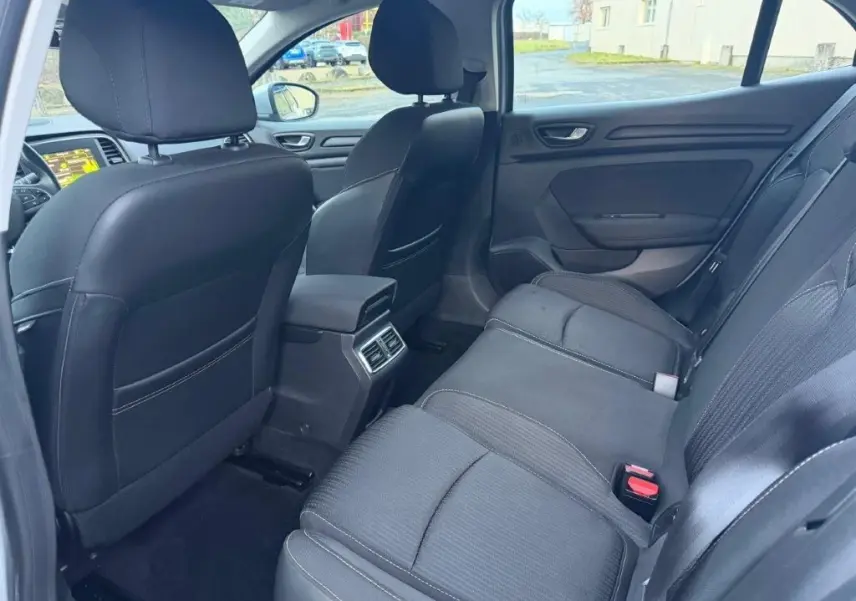 Vue intérieure arrière côté droit de la Renault Mégane Business gris alu, montrant les sièges noirs et les aérateurs centraux.