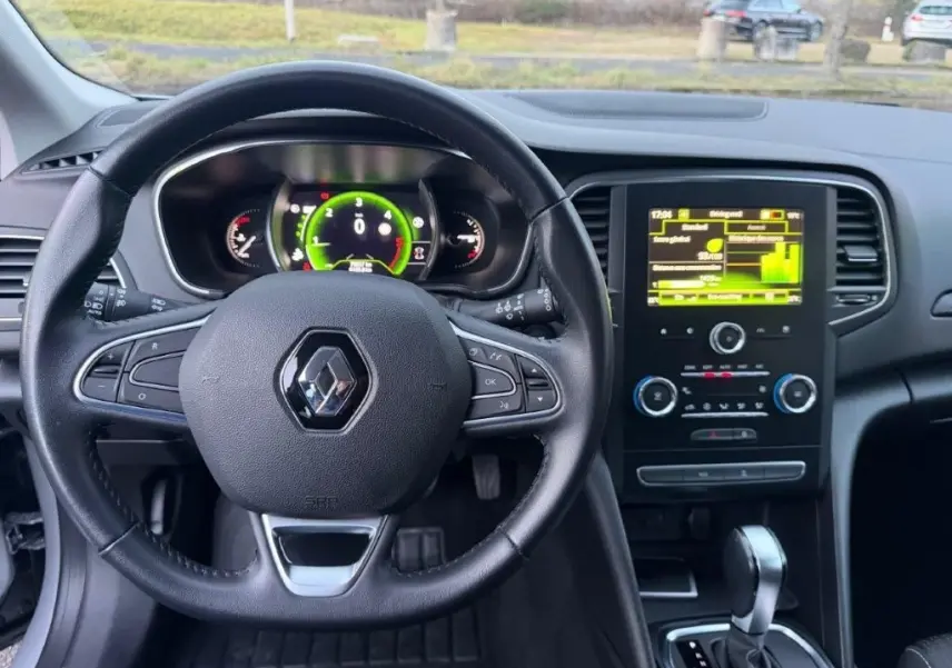 Vue intérieure centrée sur le volant noir de la Renault Mégane Business avec tableau de bord numérique et écran tactile.