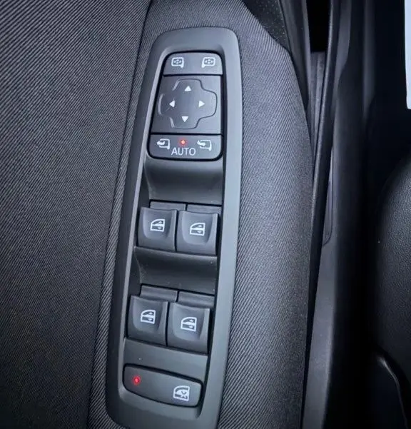Gros plan sur les commandes de lève-vitres et rétroviseurs électriques sur la porte côté gauche d’une Renault Mégane Business gris alu.