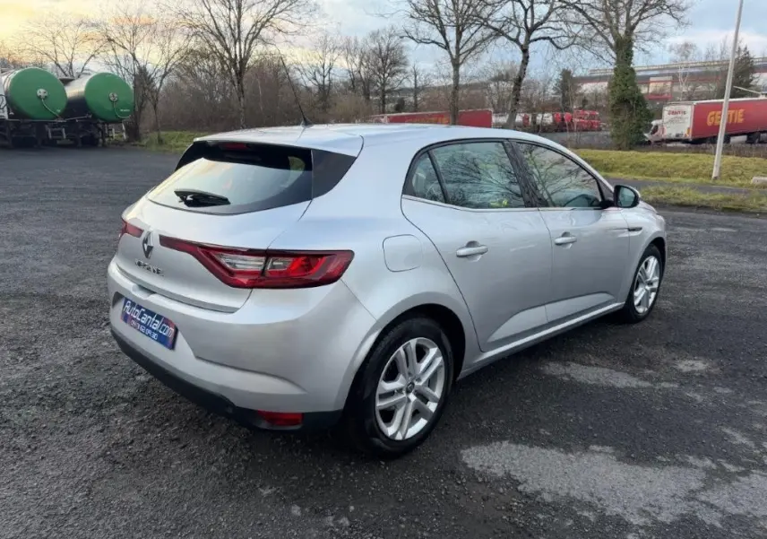 Vue 3/4 arrière droite d'une Renault Mégane Business gris alu avec feux arrière LED et jantes alliage sur parking extérieur.
