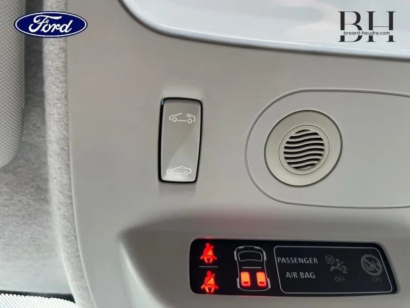 Détail du plafonnier gris avec commande d'ouverture de toit ouvrant et témoins lumineux de ceinture et airbag passager.