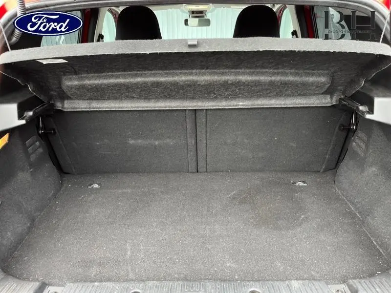 Coffre ouvert vu de l'arrière d'une Renault Twingo Rouge Flamme avec toit ouvrant en toile visible.