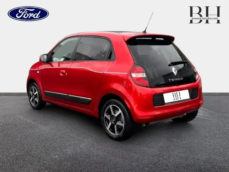 Vue 3/4 arrière gauche d'une Renault Twingo rouge flamme avec toit ouvrant et jantes alu noires.