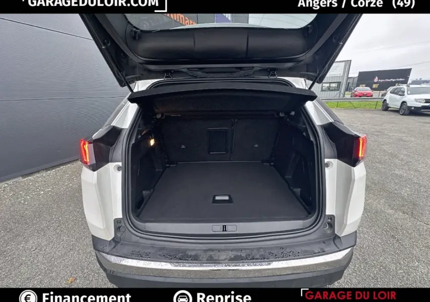 Vue arrière du coffre ouvert d'un Peugeot 3008 blanc, mettant en valeur l'espace de chargement vide et l'éclairage intérieur.
