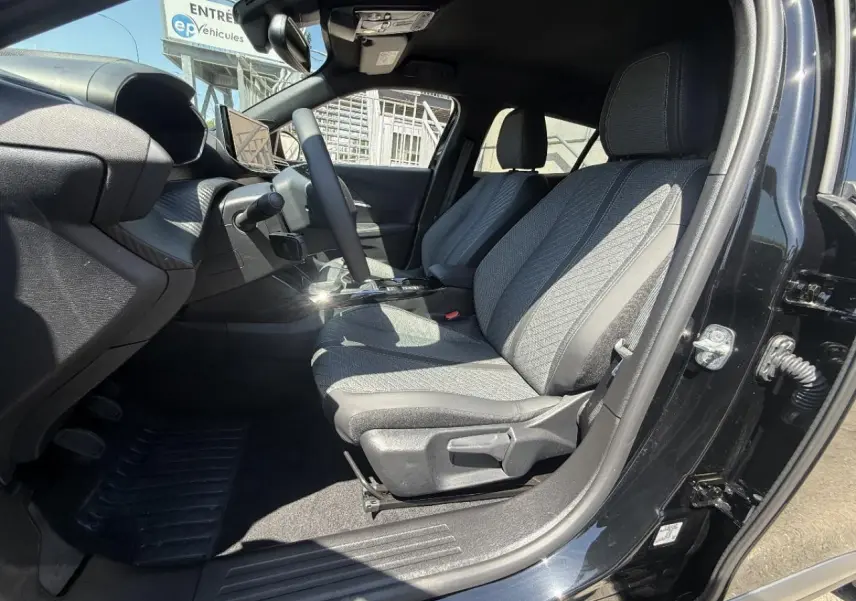 Intérieur du Peugeot 2008 2024 noir perla, vue côté conducteur ouverte sur les sièges avant en tissu gris.