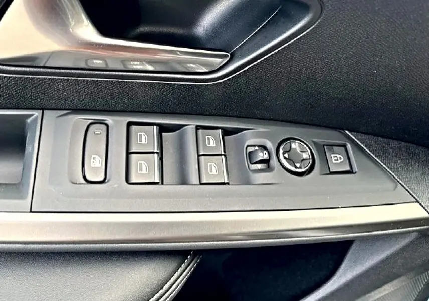 Gros plan sur la commande des vitres et rétroviseurs côté gauche d’une Peugeot 3008 gris titane, intérieur noir.