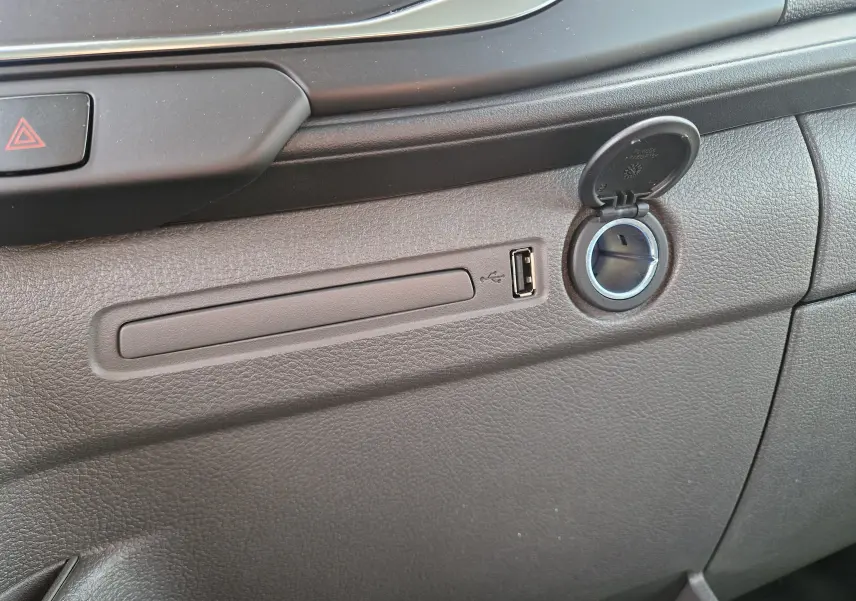 Détail de la console intérieure grise du Ford Transit Chassis Cabine 2026, avec prise USB et allume-cigare ouvert.