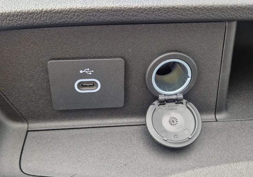 Gros plan intérieur sur la prise USB-C et l’allume-cigare avec couvercle ouvert du Ford Transit Châssis Cabine blanc.