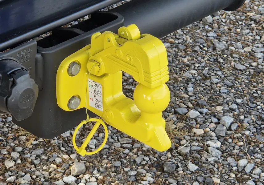 Gros plan sur l'attelage jaune fixé à l'arrière du Ford Transit Châssis Cabine blanc, posé sur un sol en gravier.