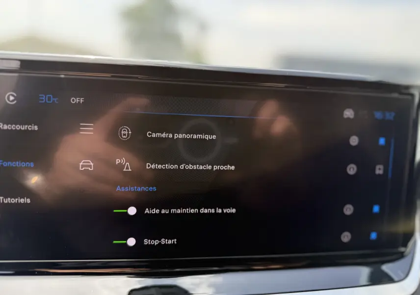 Écran tactile du tableau de bord de la Peugeot 208 Hybrid 145 GT, affichant les assistances à la conduite activées.