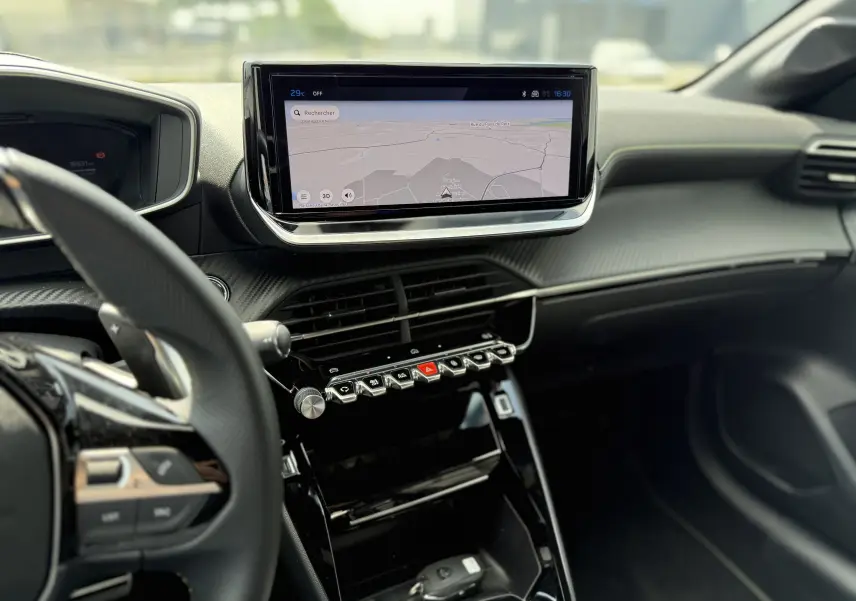 Vue intérieure du tableau de bord de la Peugeot 208 Hybrid 145 GT avec écran tactile et commandes piano noires.