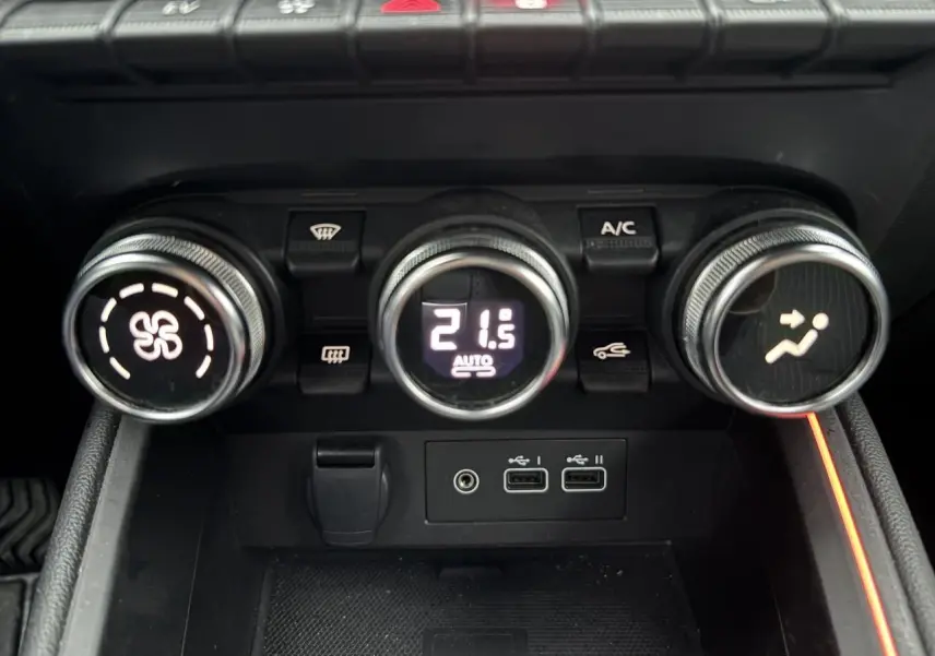 Gros plan sur les commandes de climatisation avec affichage digital et ports USB de la Renault Clio V rouge flamme.