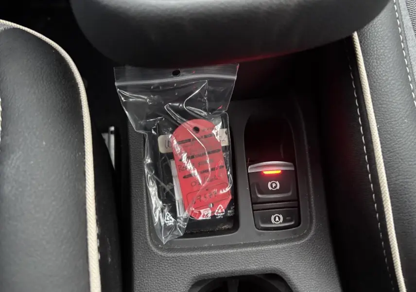 Gros plan sur la console centrale de la Renault Clio rouge flamme, avec bouton de frein à main électronique allumé.