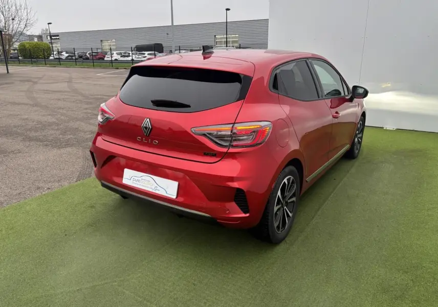 Vue 3/4 arrière droite d'une Renault Clio rouge flamme métal avec feux arrière LED et jantes alliage 16 pouces.