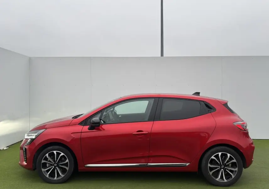 Profil droit d'une Renault Clio V 1.6 E-TECH Full Hybrid 2025 en rouge flamme métal avec jantes alliage 16 pouces.