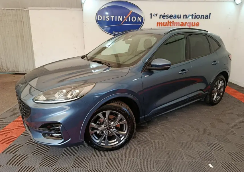 Vue 3/4 avant d'un Ford Kuga bleu 2024 finition St Line avec jantes alliage et vitres teintées en showroom.