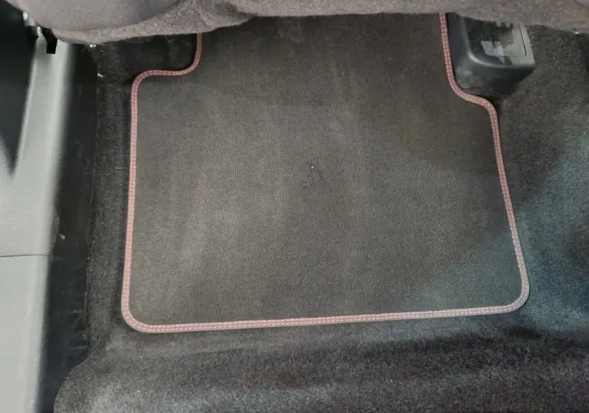 Tapis de sol noir avec surpiqûres rouges dans l'habitacle avant d'un Ford Kuga bleu 2024.