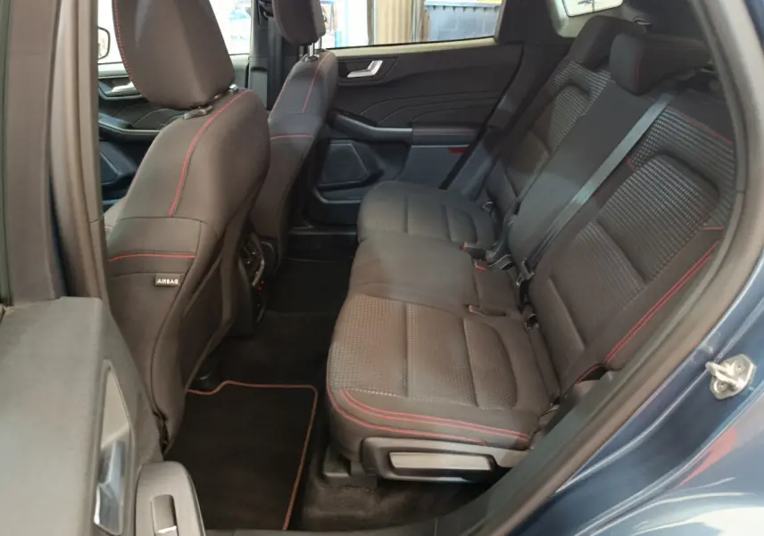 Vue côté gauche des sièges arrière noirs avec surpiqûres rouges du Ford Kuga 2024 bleu, finition St Line
