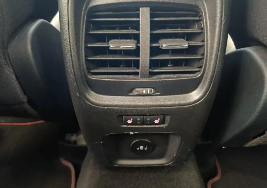 Gros plan sur la console arrière noire du Ford Kuga bleu 2024 avec aérateurs, commandes chauffantes et prise USB.