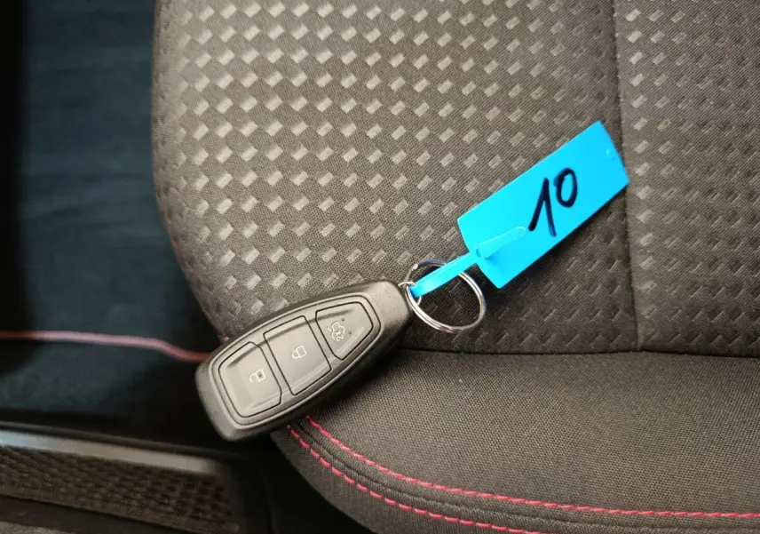 Télécommande de clé Ford posée sur siège tissu noir avec surpiqûres rouges dans un Ford Kuga 2024 St Line.