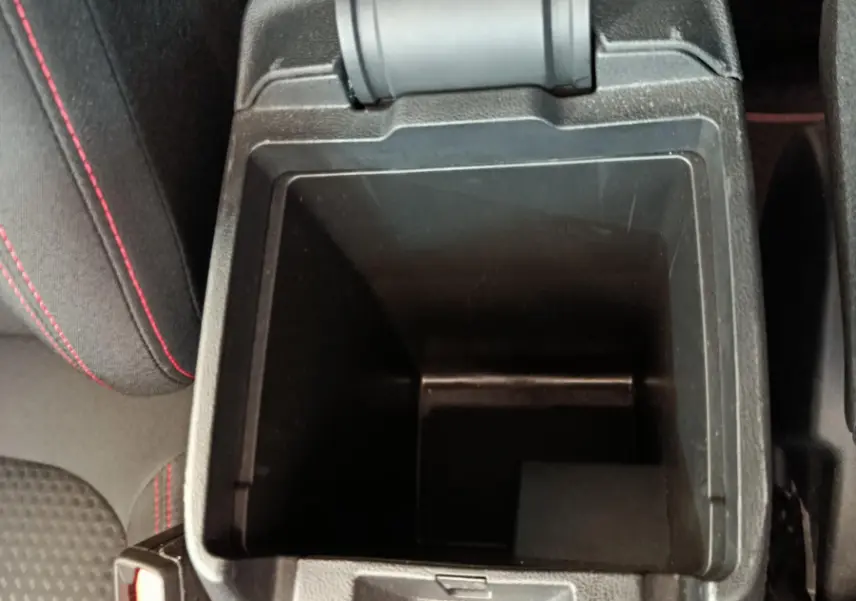 Vue plongeante sur la console centrale ouverte du Ford Kuga 2024 bleu, avec surpiqûres rouges sur siège noir.