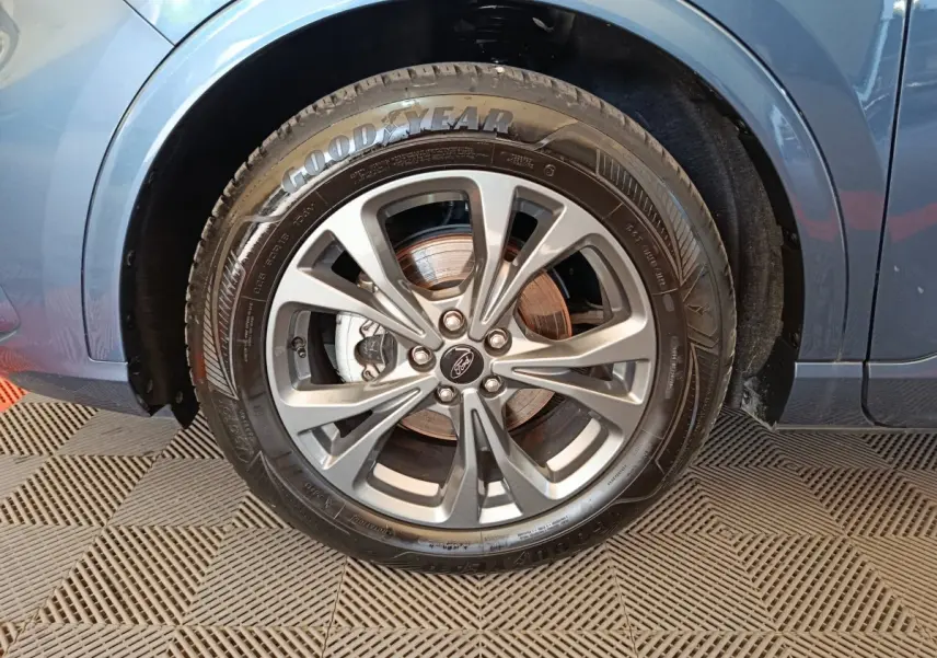 Gros plan sur la roue avant droite du Ford Kuga bleu 2024, mettant en valeur la jante alliage et le pneu Goodyear.
