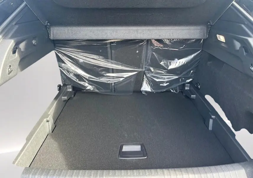 Coffre ouvert du Peugeot 3008 gris Artense, vue de l'intérieur montrant le plancher plat et les protections plastiques.