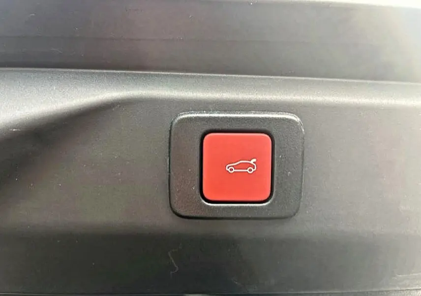 Bouton rouge d'ouverture électrique du coffre sur le hayon arrière du Peugeot 3008 gris Artense 2025.