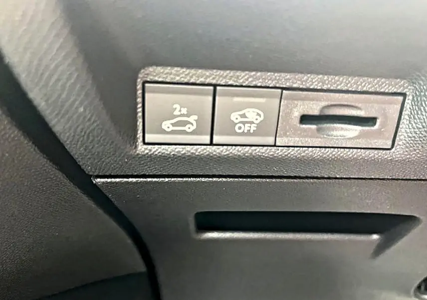 Gros plan sur les commandes d'ouverture du coffre et de désactivation de l'assistance au freinage dans un Peugeot 3008 gris Artense.