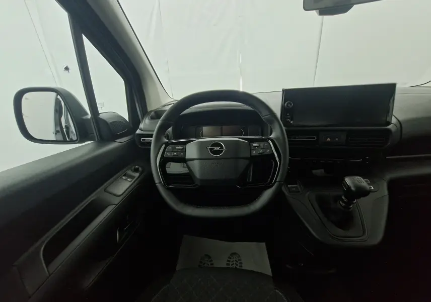 Vue intérieure centrée sur le volant et tableau de bord de l'Opel Combo Life avec boîte manuelle et écran tactile.