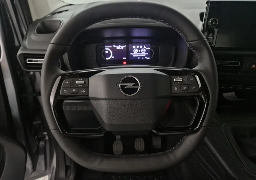 Vue rapprochée du volant en cuir noir de l'Opel Combo Life gris Artense avec tableau de bord digital allumé.