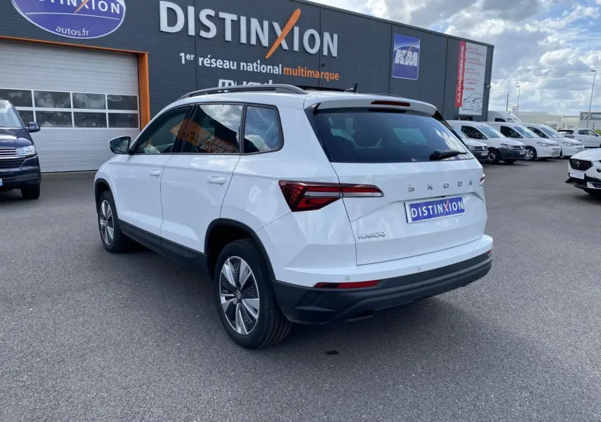 Vue 3/4 arrière droite d'un Skoda Karoq blanc moon métallisé avec jantes alliage et toit ouvrant panoramique.