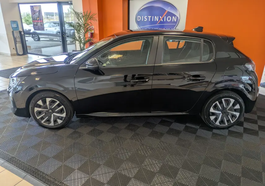 Peugeot 208 PureTech 100 noir perla vue de profil côté gauche en intérieur avec jantes alliage et rétroviseurs rabattables.