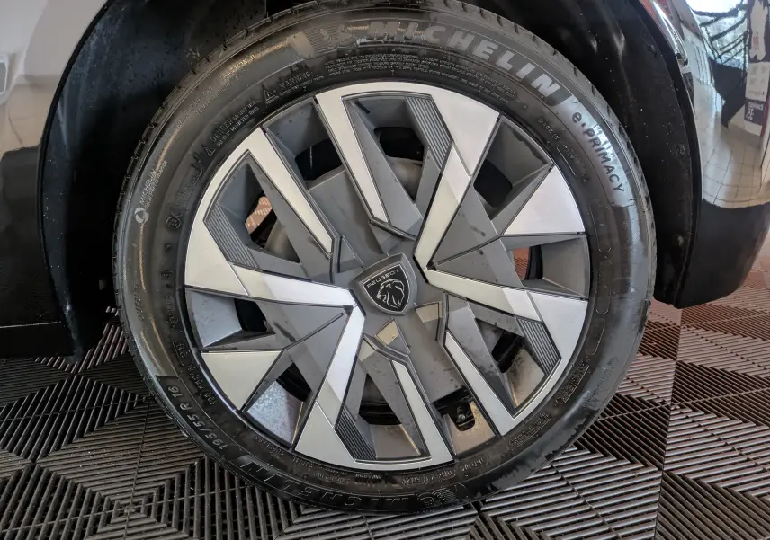 Gros plan sur la jante alliage 16 pouces de la Peugeot 208 PureTech 100 noire, avec logo lion central visible.
