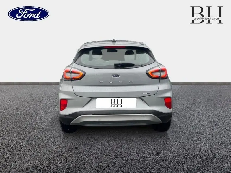 Vue arrière d'un Ford Puma 2023 gris Solar Métallisée avec feux allumés et logo visible sur fond neutre.