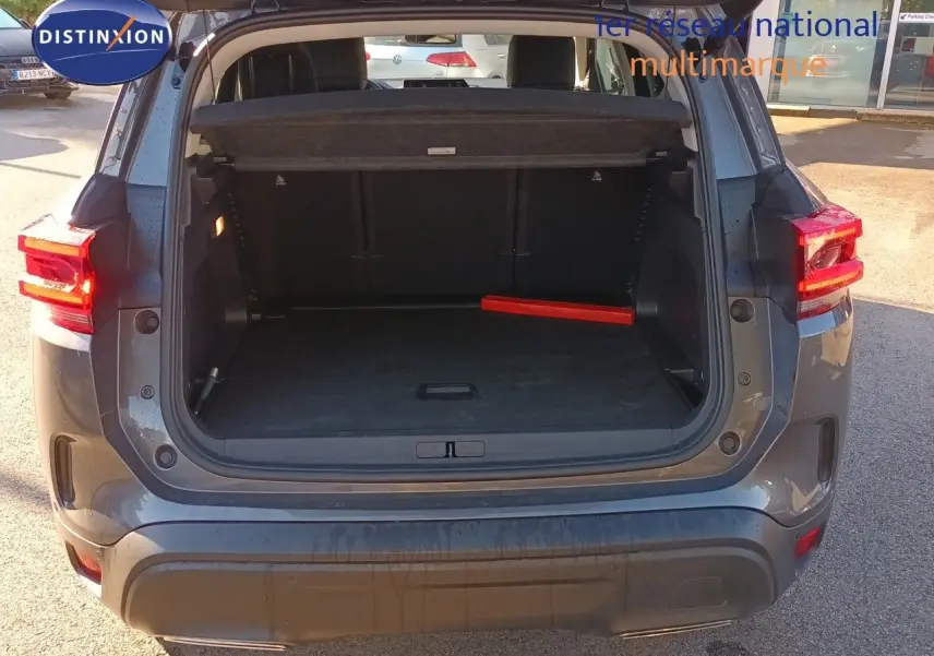 Coffre ouvert vu de l'arrière d'un Citroën C5 Aircross gris platinium métal avec feu arrière allumé.