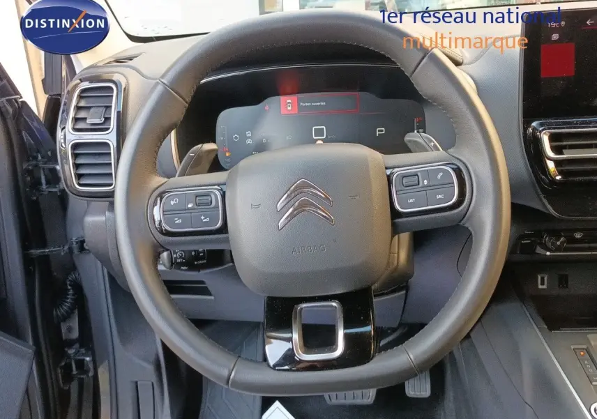 Vue centrée sur le volant cuir noir du Citroën C5 Aircross 2025, avec tableau de bord digital et commandes intégrées.