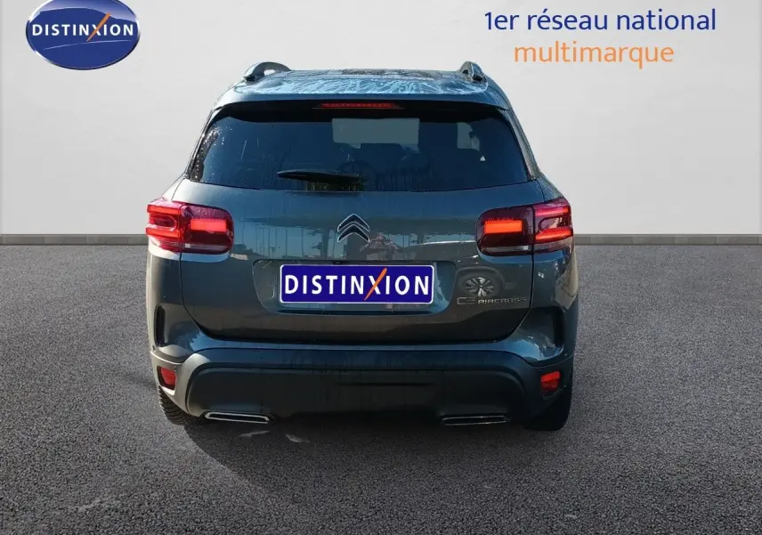 Vue arrière d'un Citroën C5 Aircross gris platinium métal 2025 avec feux arrière allumés et double sortie d'échappement.