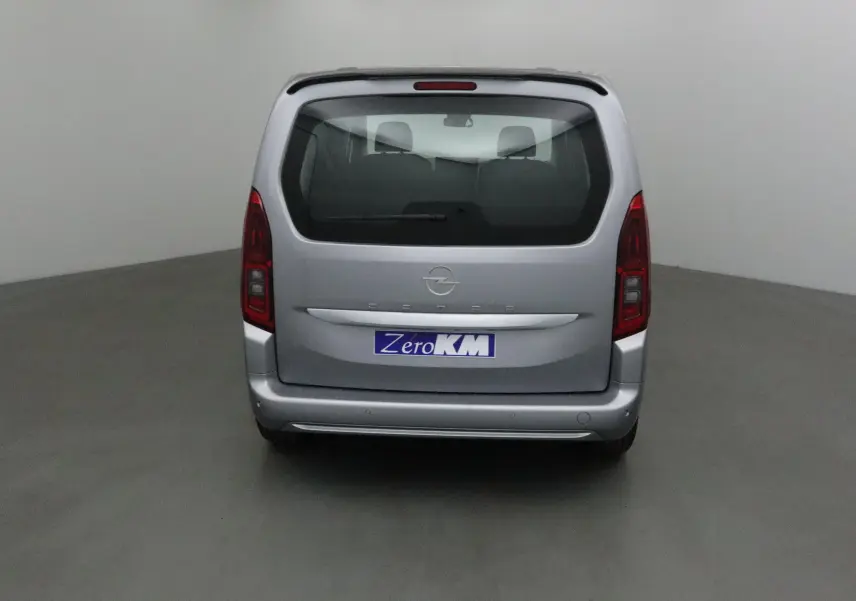 Vue arrière d'un Opel Combo Life gris Artense avec becquet et feux arrière verticaux dans un studio.