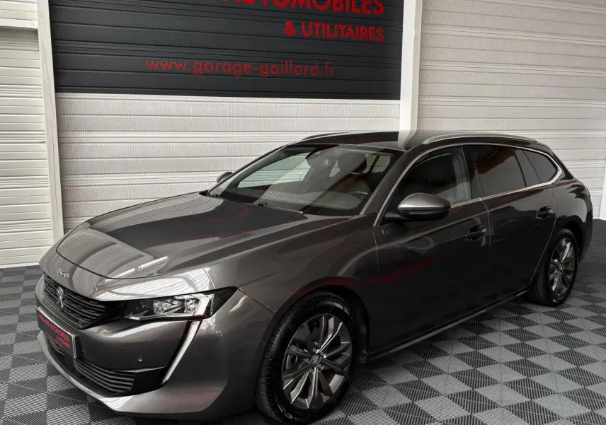 Peugeot 508 gris foncé vue 3/4 avant droit, avec jantes alliage et calandre noire brillante.