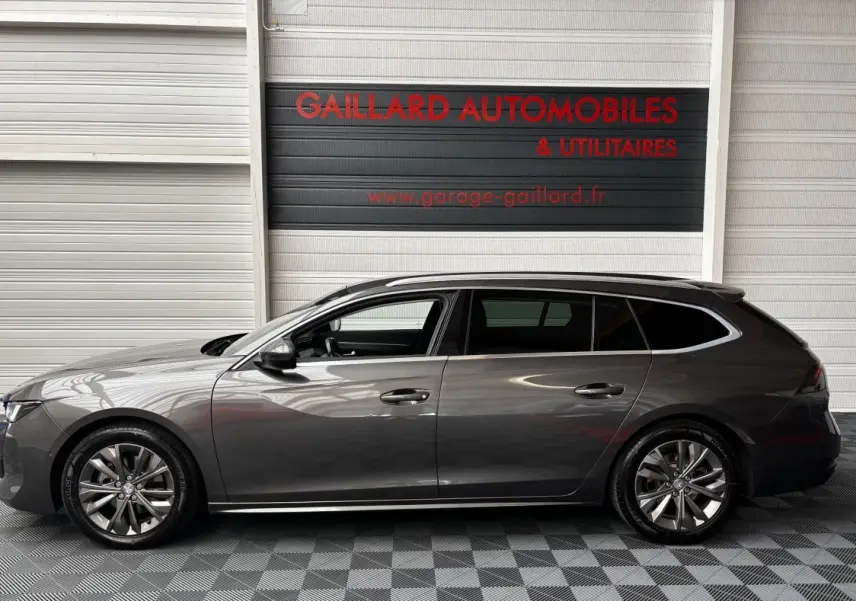 Profil côté gauche d'une Peugeot 508 break gris foncé 2019 garée en intérieur avec jantes alliage et vitres teintées.