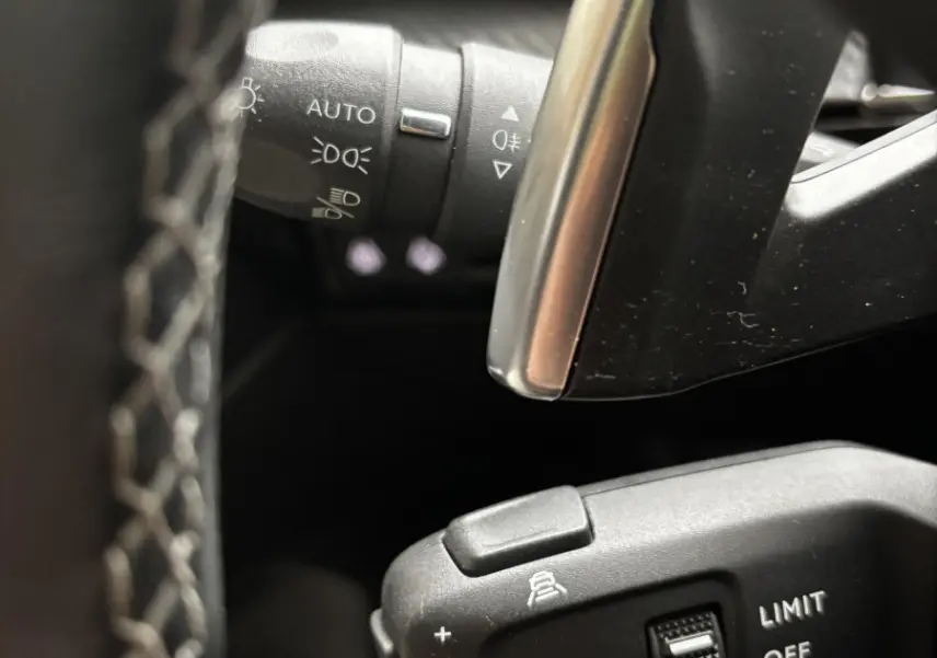 Gros plan sur commandes au volant noir et gris de la Peugeot 508 BlueHDi 2019, avec réglages croisière et phares automatiques.