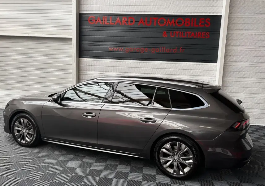 Peugeot 508 break gris foncé vue de profil côté gauche dans un showroom avec sol damier noir et gris.