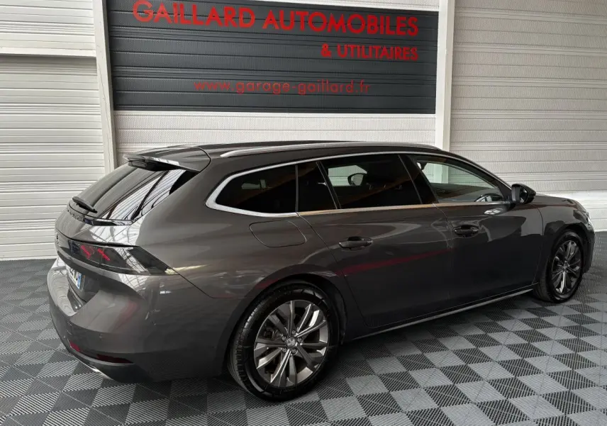 Peugeot 508 SW gris foncé vue 3/4 arrière droit dans un garage avec jantes alliage et vitres teintées.