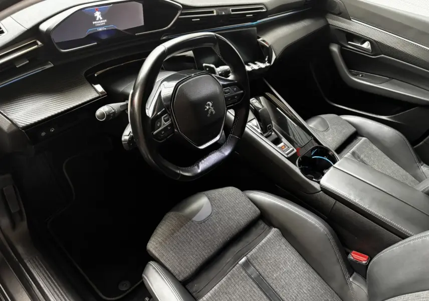 Intérieur de Peugeot 508 gris foncé vu côté conducteur, volant compact et tableau de bord numérique lumineux.