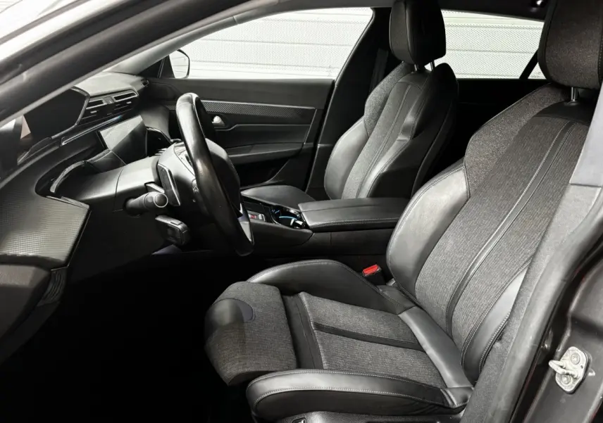 Intérieur de la Peugeot 508 2019, vue côté conducteur, sièges tissu et cuir gris, tableau de bord moderne noir mat.