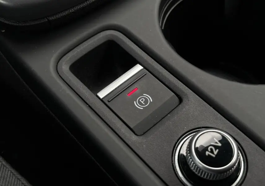 Gros plan sur le bouton de frein à main électronique et prise 12V dans la console centrale d'une Audi A3 Berline 2024.