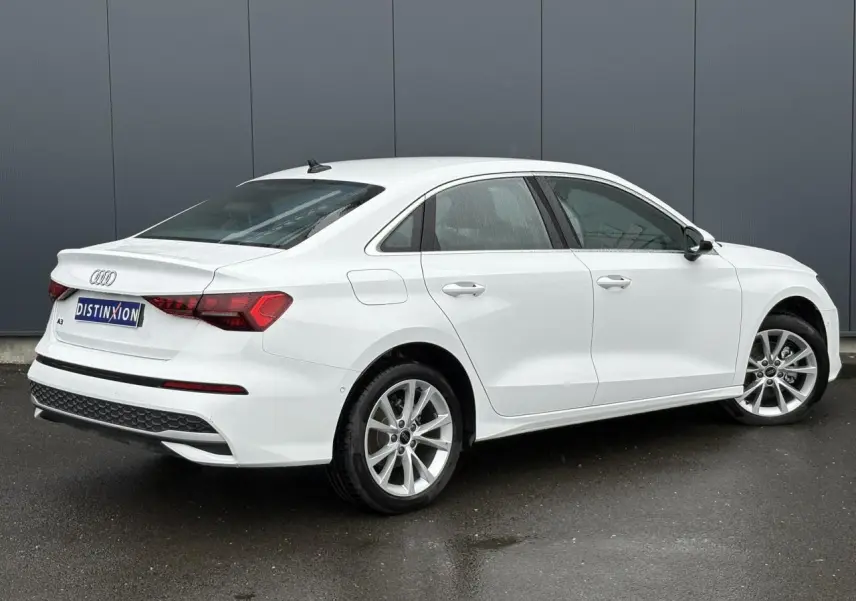 Audi A3 Berline blanc Arkona vue 3/4 arrière droit, mettant en valeur les feux LED et jantes alliage 17 pouces.