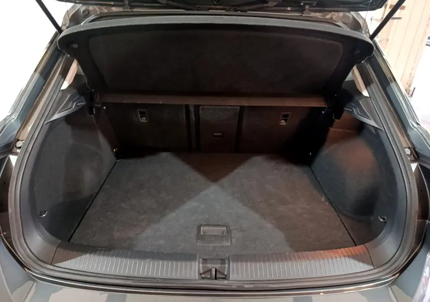 Vue arrière du coffre ouvert du Volkswagen T-ROC gris foncé, montrant un espace de chargement propre et spacieux.