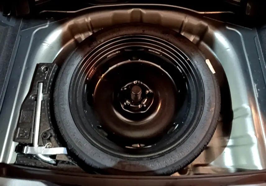 Vue plongeante sur la roue de secours galette noire dans le coffre gris foncé du Volkswagen T-Roc 2022.